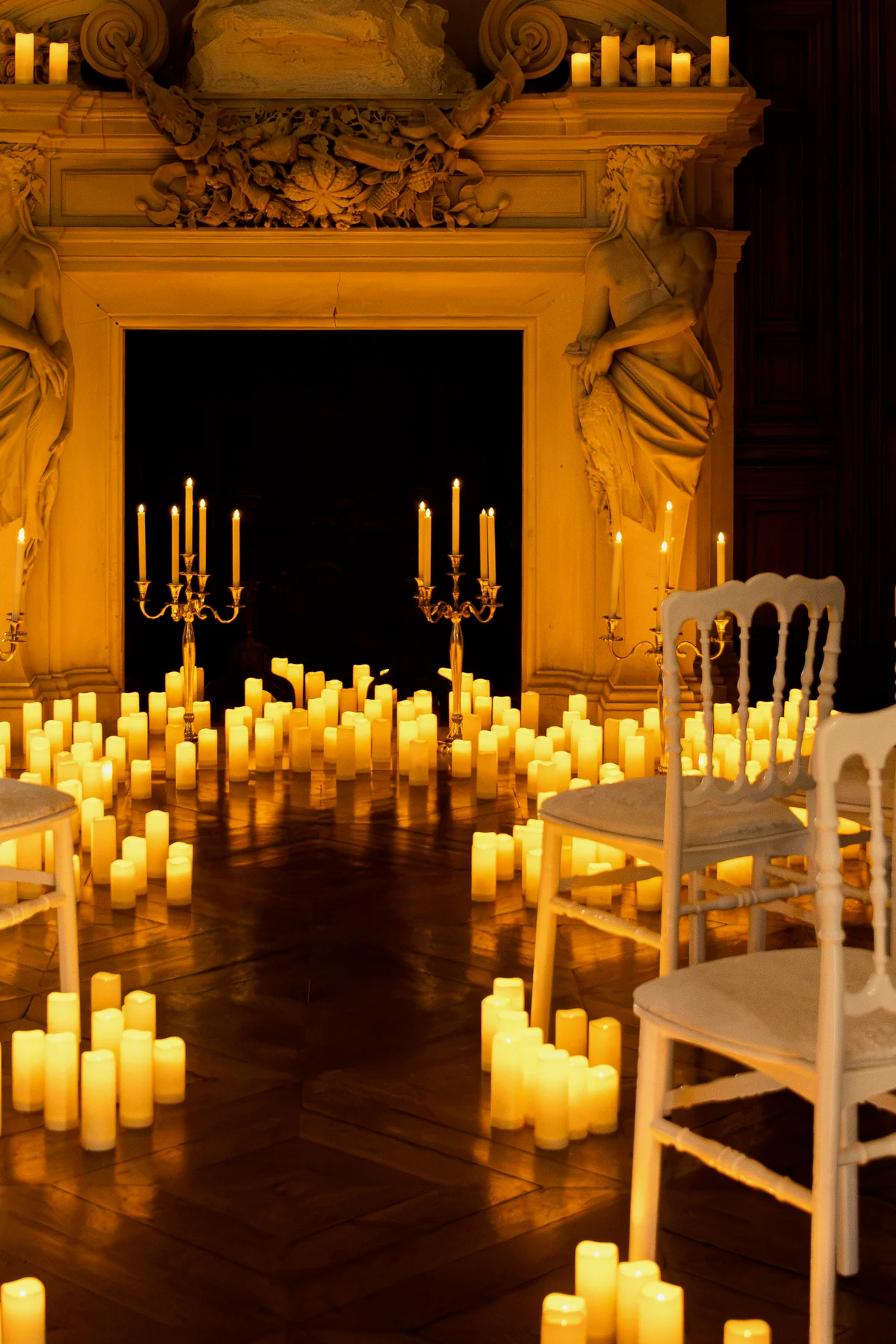 Une cheminée sculptée et des chaises entourées de bougies pour le concert